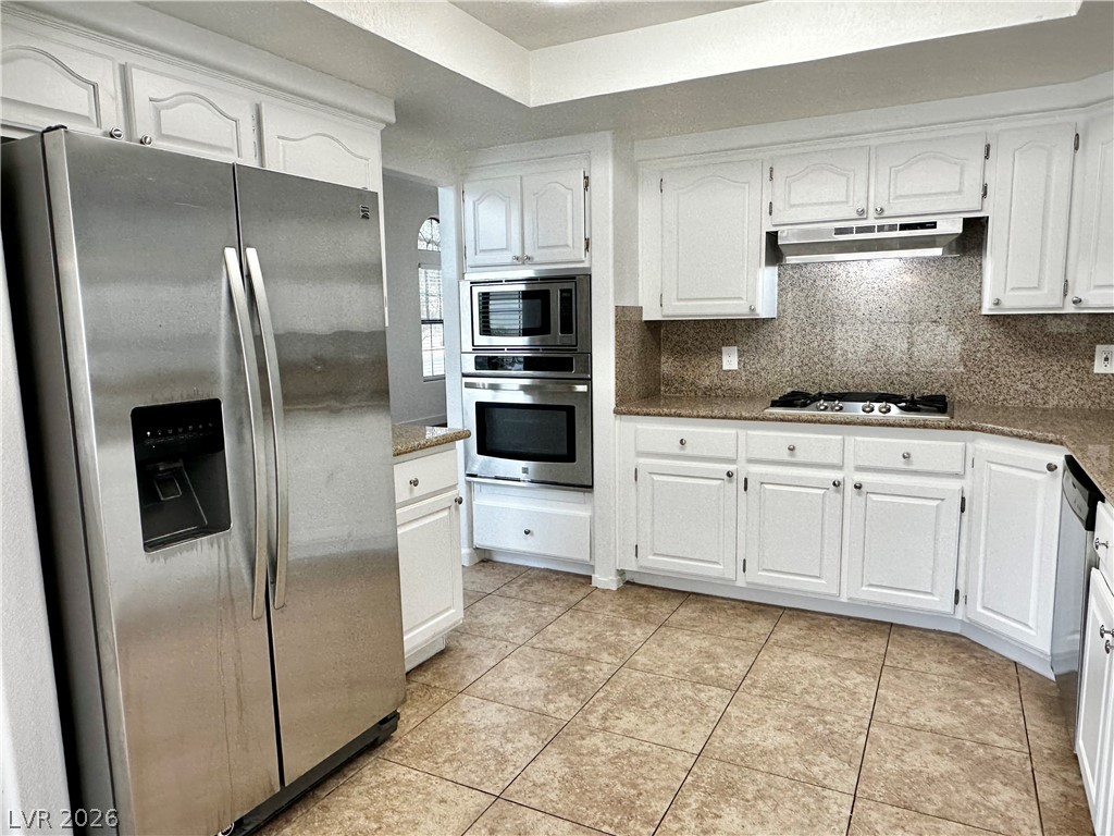 2113 Rico Peak Court Las Vegas, NV 89128 - Photo 24 of 53 Kitchen with stainless steel appliances, white cabinetry, decorative backsplash, and dark stone counters