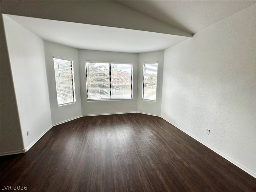2113 Rico Peak Court Las Vegas, NV 89128 - Photo 32 of 53 Spare room featuring dark wood-type flooring, vaulted ceiling, and a textured wall