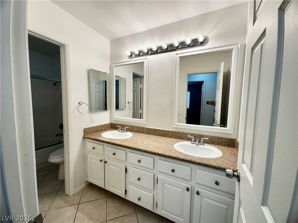 2113 Rico Peak Court Las Vegas, NV 89128 - Photo 36 of 53 Full bath featuring double vanity, light tile patterned flooring, and washtub / shower combination
