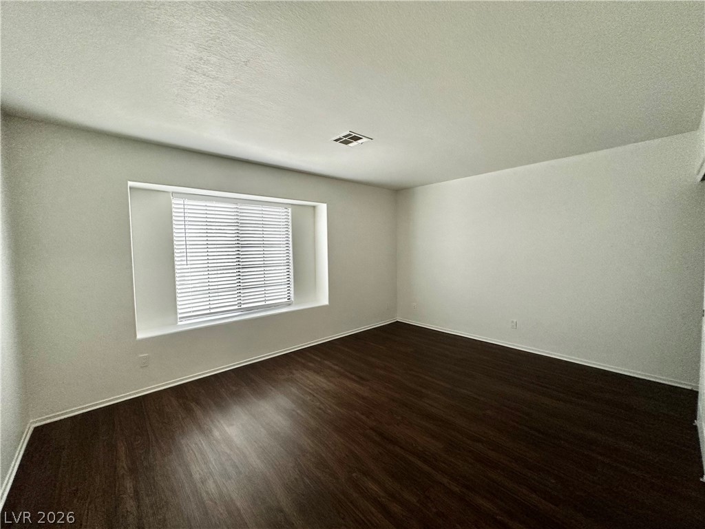 2113 Rico Peak Court Las Vegas, NV 89128 - Photo 37 of 53 Spare room featuring a textured ceiling and dark wood-type flooring
