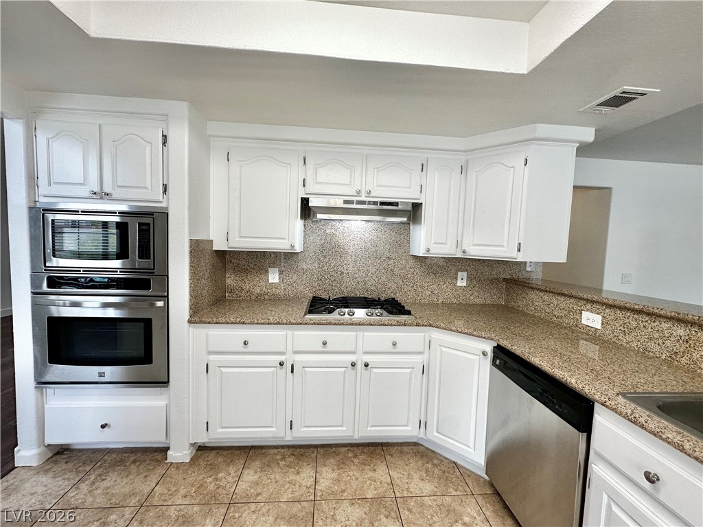 2113 Rico Peak Court Las Vegas, NV 89128 - Photo 4 of 53 Kitchen featuring white cabinetry, decorative backsplash, stainless steel appliances, and light tile patterned floors
