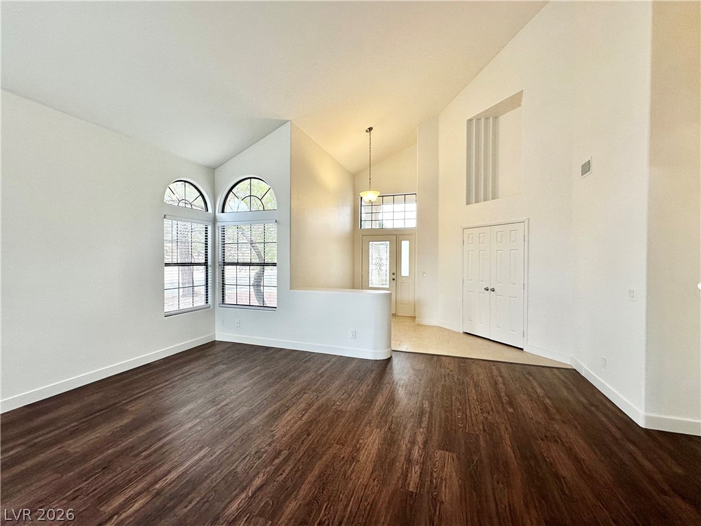 2113 Rico Peak Court Las Vegas, NV 89128 - Photo 9 of 53 Unfurnished living room featuring vaulted ceiling and dark wood-style floors
