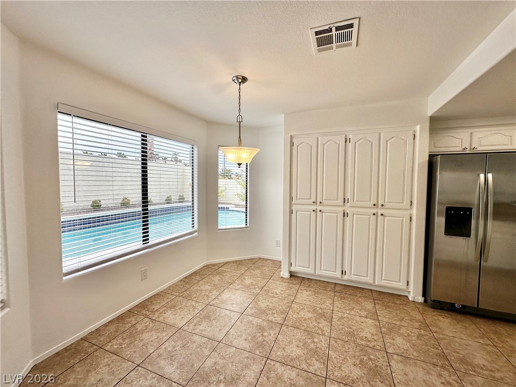 2113 Rico Peak Court Las Vegas, NV 89128 - Photo 10 of 53 Unfurnished dining area featuring light tile patterned flooring and a textured ceiling