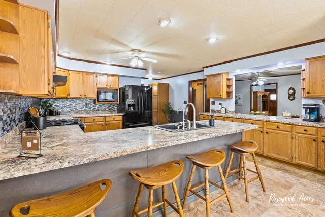 a large kitchen with granite countertop a sink and chairs