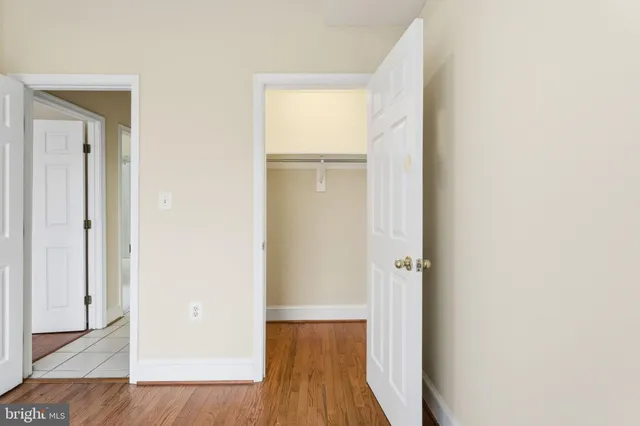 a view of a hallway with wooden floor and a bathroom