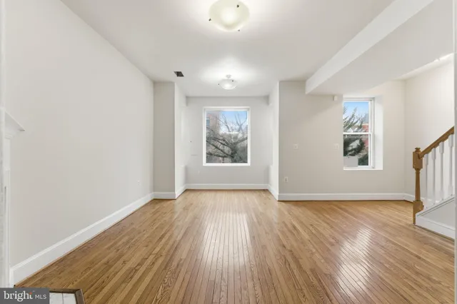 an empty room with wooden floor and windows
