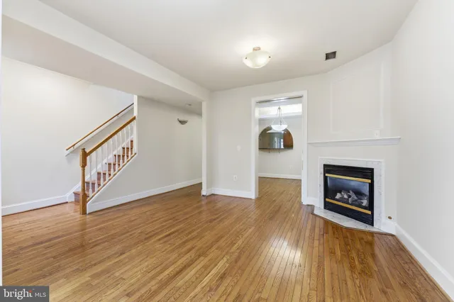 a view of an empty room fire place and wooden floor