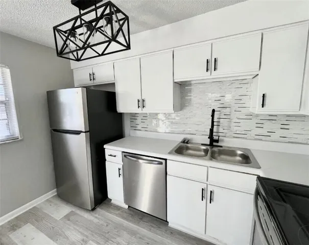 a kitchen with stainless steel appliances granite countertop white cabinets and a refrigerator