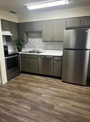 a kitchen with granite countertop a refrigerator and a stove top oven