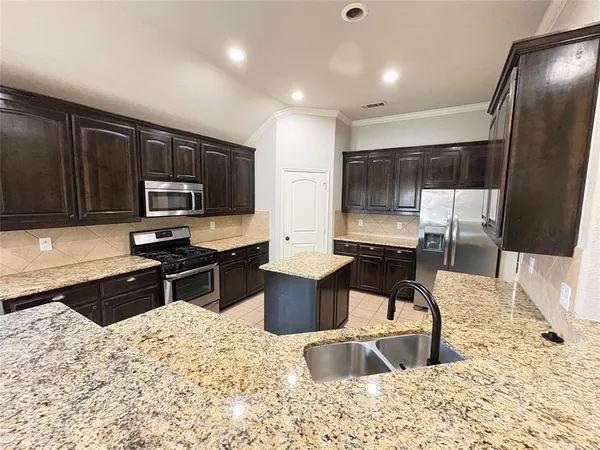 a kitchen with stainless steel appliances kitchen island granite countertop a stove sink and cabinets