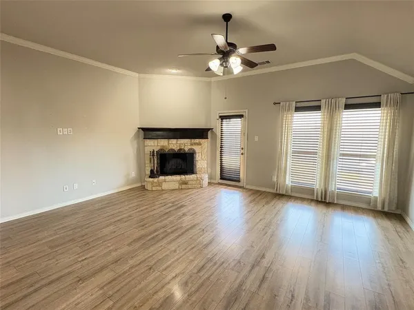 an empty room with wooden floor fireplace and windows