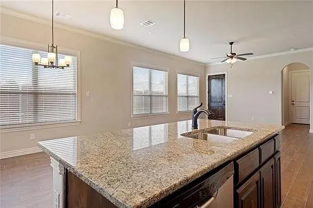 a kitchen with granite countertop kitchen island a counter space windows and a chandelier