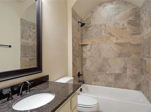 a bathroom with a granite countertop sink toilet and shower