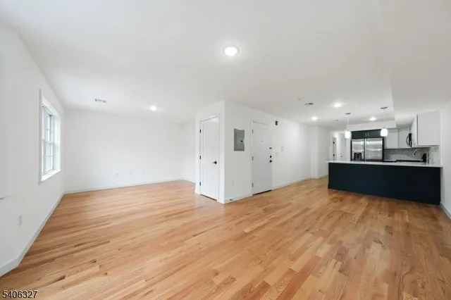 a view of kitchen and empty room with wooden floor