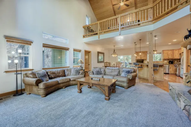 a kitchen with stainless steel appliances granite countertop a stove a refrigerator a kitchen island a dining table and chairs with wooden floor