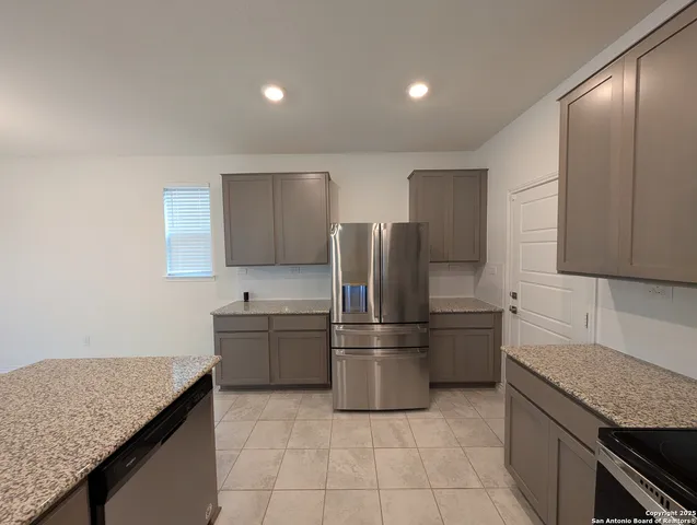 a kitchen with stainless steel appliances granite countertop a refrigerator a sink a stove a microwave and island