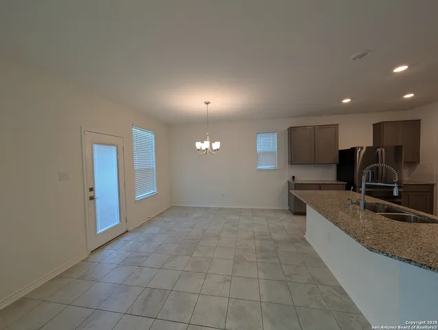 a large kitchen with granite countertop a stove a sink a window and a table