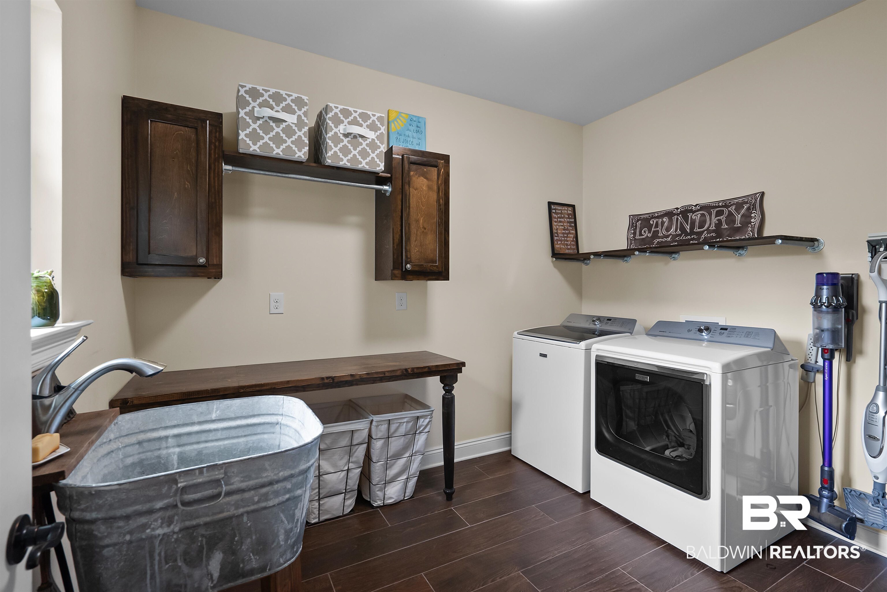 12070 Comalander Road Fairhope, AL 36532 - Photo 35 of 50 Laundry room featuring a galvanized utility sink, dark wood-finish countertop, and built-in cabinetry with a hanging rod