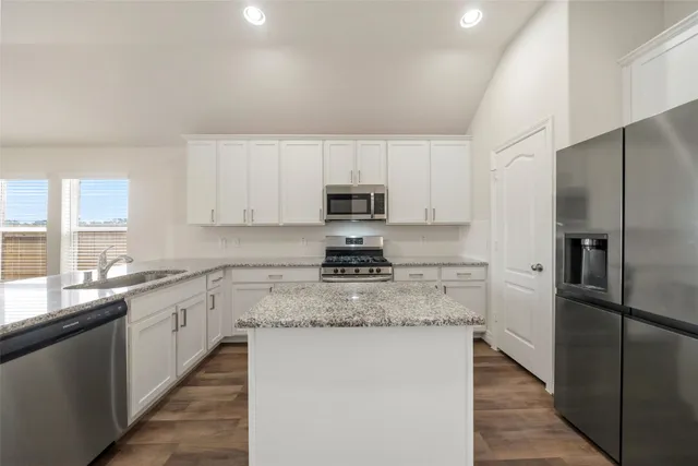 a kitchen with stainless steel appliances granite countertop a stove a sink and a refrigerator
