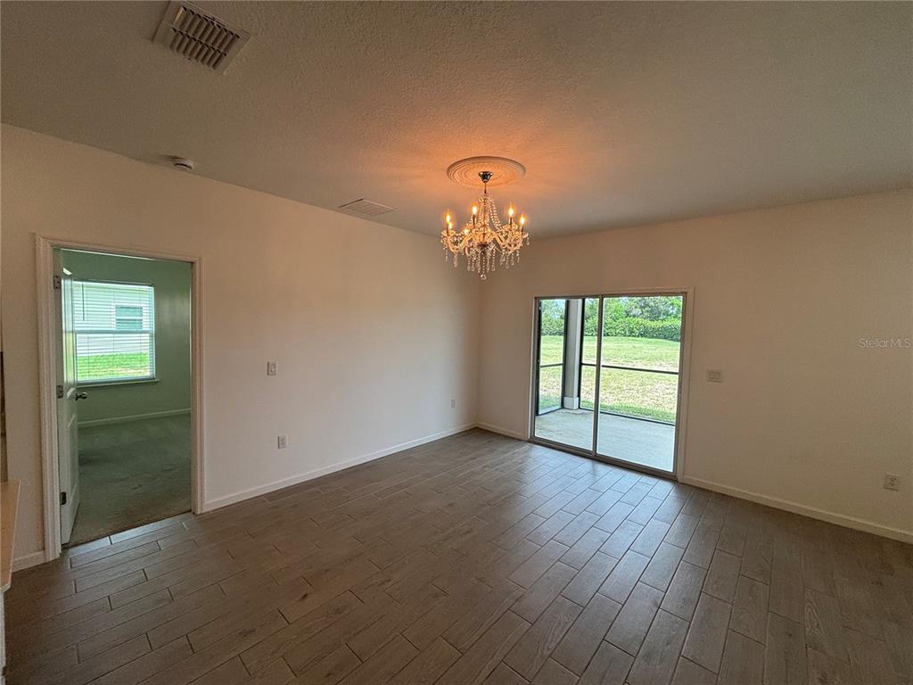 9145 Southwest 58th Circle Ocala, FL 34476 - Photo 11 of 37 an empty room with wooden floor chandelier and windows