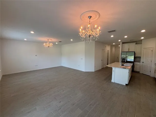 an empty room with kitchen and chandelier