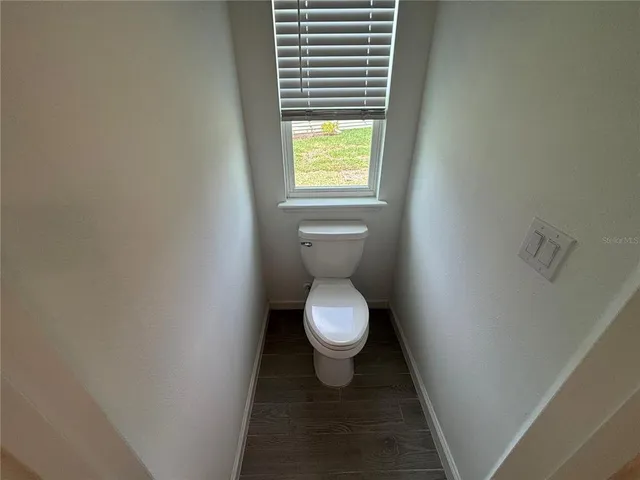 a white toilet sitting in a bathroom next to a window