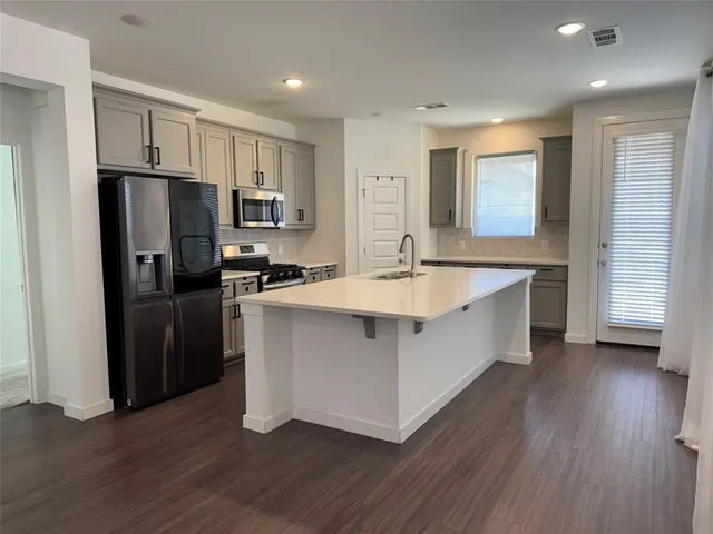 a kitchen with kitchen island a sink dishwasher a refrigerator and a stove with wooden floor