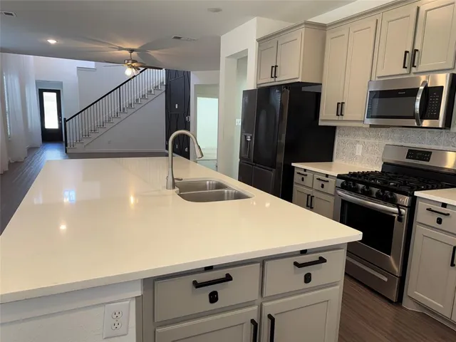 a kitchen with a sink a refrigerator and a stove top oven