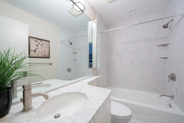 a bathroom with a granite countertop sink a toilet and shower