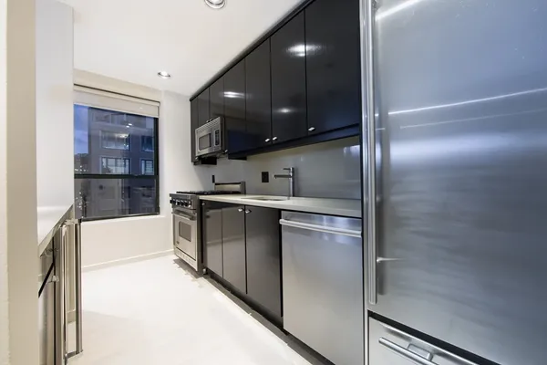 a kitchen with stainless steel appliances kitchen island granite countertop a refrigerator and a sink