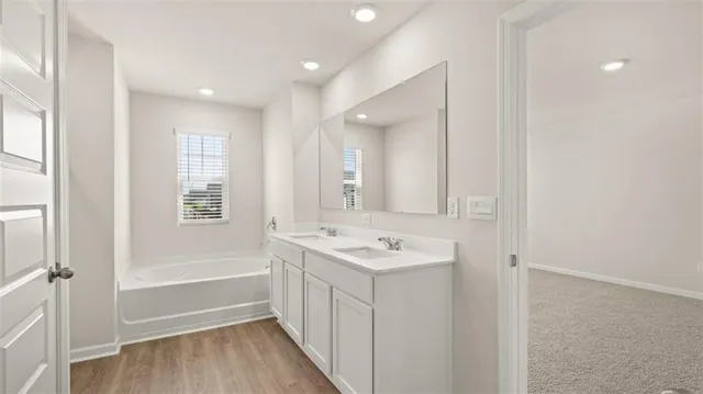 a bathroom with a double vanity sink a mirror and a bathtub
