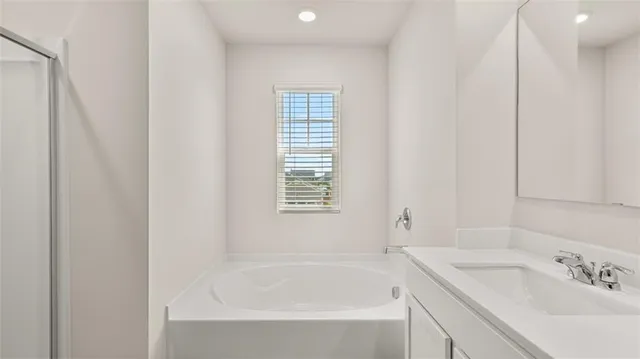 a white bath tub sitting next to a white sink and vanity