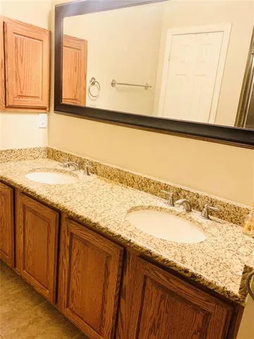 a bathroom with a granite countertop sink and a large mirror