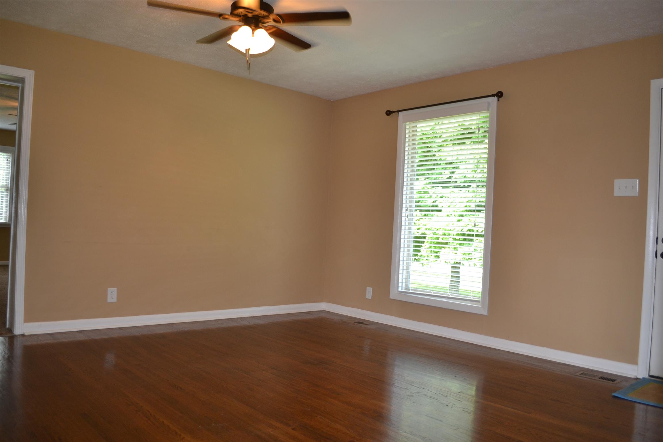5089 Trough Springs Road Adams, TN 37010 - Photo 3 of 30 an empty room with wooden floor chandelier fan and windows