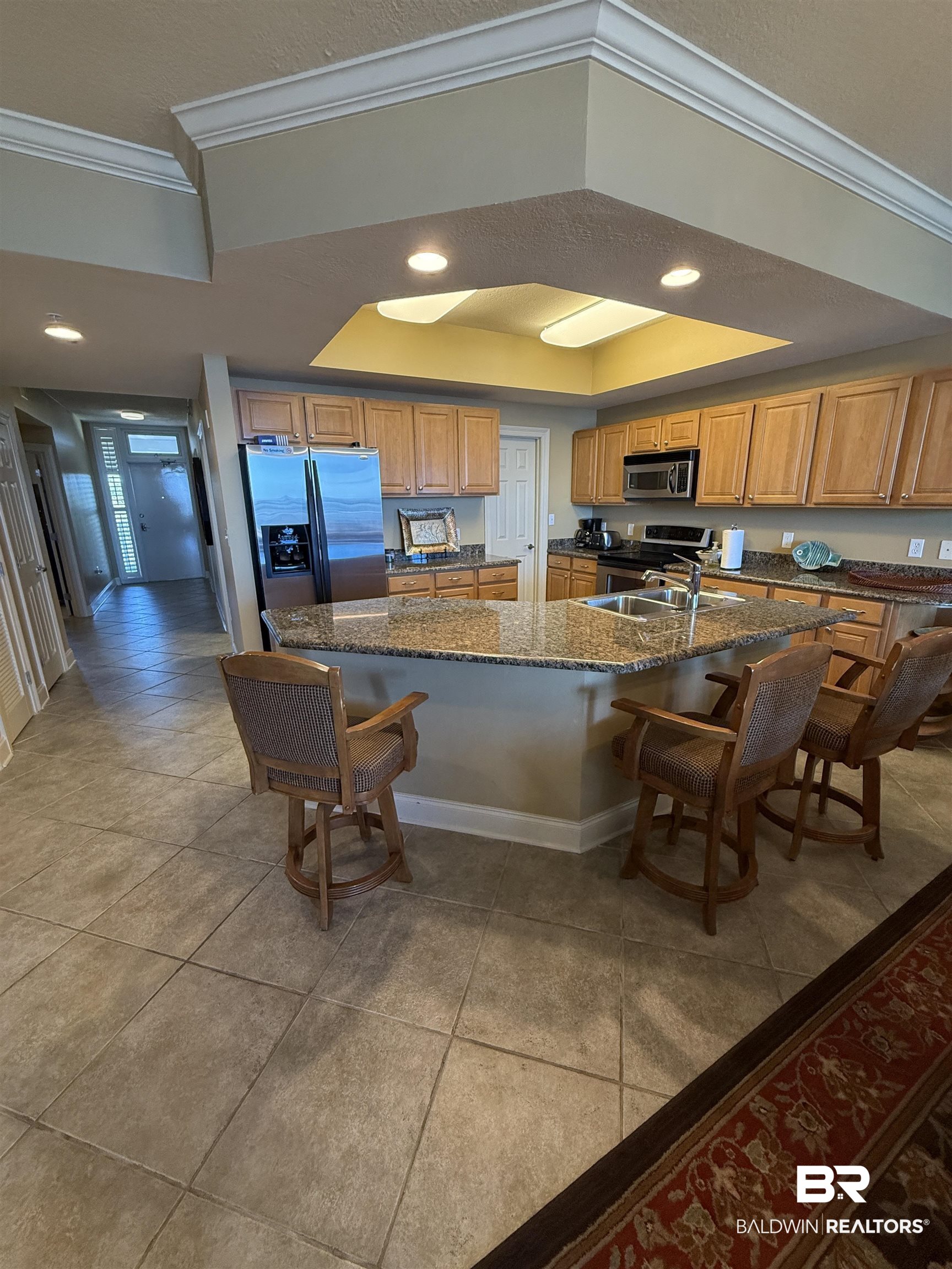 27800 Canal Road, Unit 409 Orange Beach, AL 36561 - Photo 20 of 22 Kitchen featuring a breakfast bar, crown molding, light tile patterned floors, stainless steel appliances, and a tray ceiling