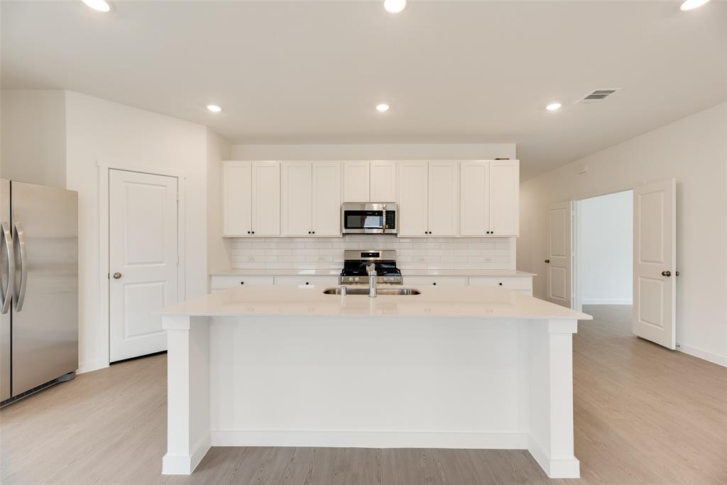 2416 Conroe Road Celina, TX 75009 - Photo 11 of 28 a kitchen with stainless steel appliances a refrigerator sink stove and white cabinets