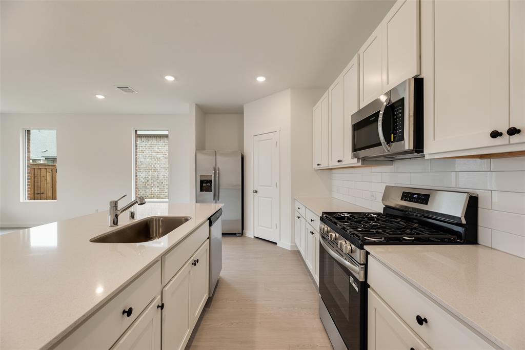 2416 Conroe Road Celina, TX 75009 - Photo 13 of 28 a kitchen with stainless steel appliances granite countertop a sink a microwave and cabinets