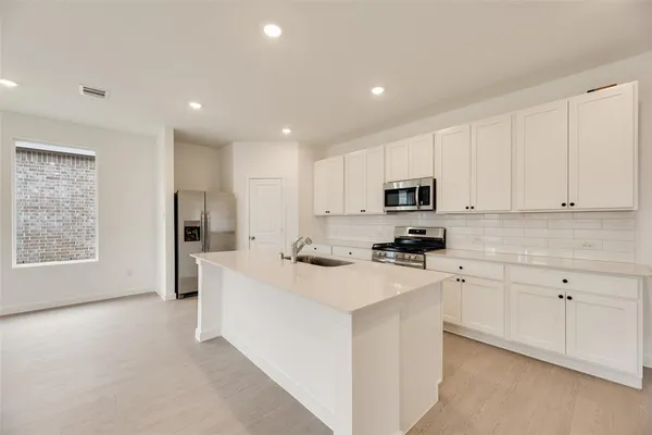 a kitchen with stainless steel appliances white cabinets and a refrigerator