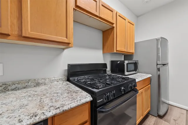a kitchen with granite countertop a stove a refrigerator and a sink