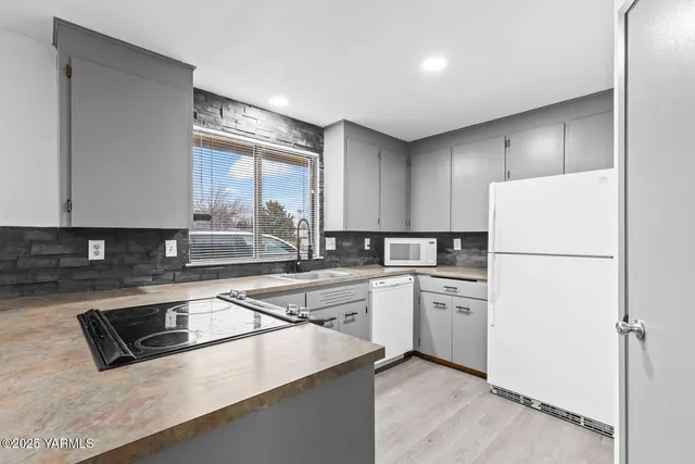 a kitchen with a sink a stove a refrigerator and white cabinets