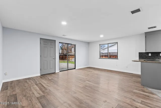 a view of an empty room with a window and wooden floor