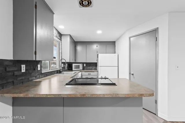 a kitchen with kitchen island granite countertop a sink a stove and a refrigerator