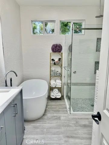 a bathroom with a tub a window and glass door shower