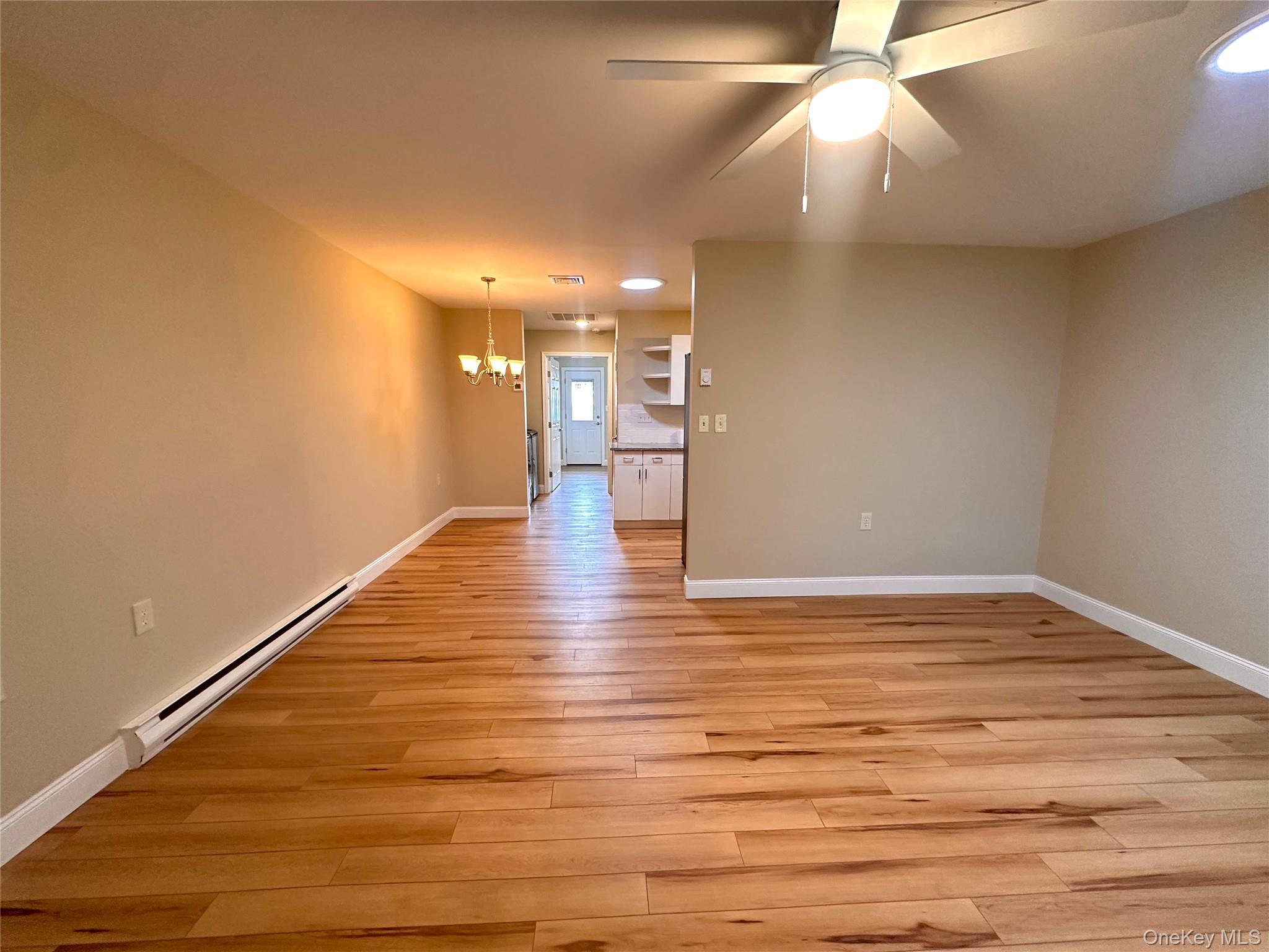 312 Woodbridge Drive, Unit C Ridge, NY 11961 - Photo 4 of 12 a view of an empty room with wooden floor and a ceiling fan