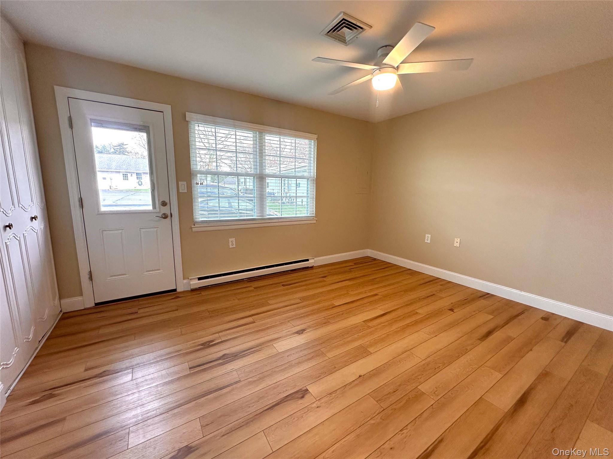 312 Woodbridge Drive, Unit C Ridge, NY 11961 - Photo 8 of 12 an empty room with wooden floor and windows