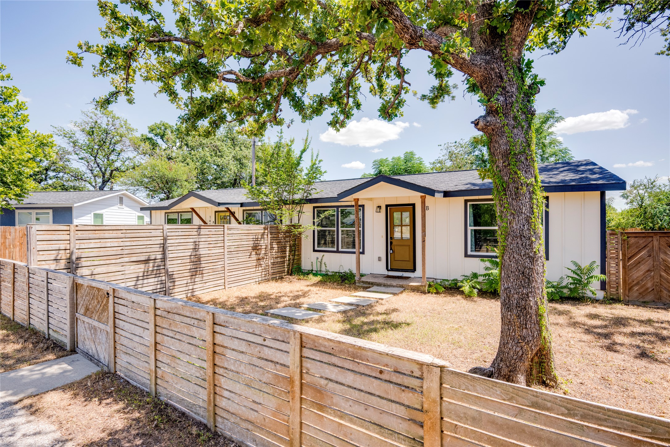 1400 Marcus Place, Unit B Austin, TX 78721 - Photo 7 of 39 A quaint residence featuring a welcoming entry, framed by established trees and a privacy fence.