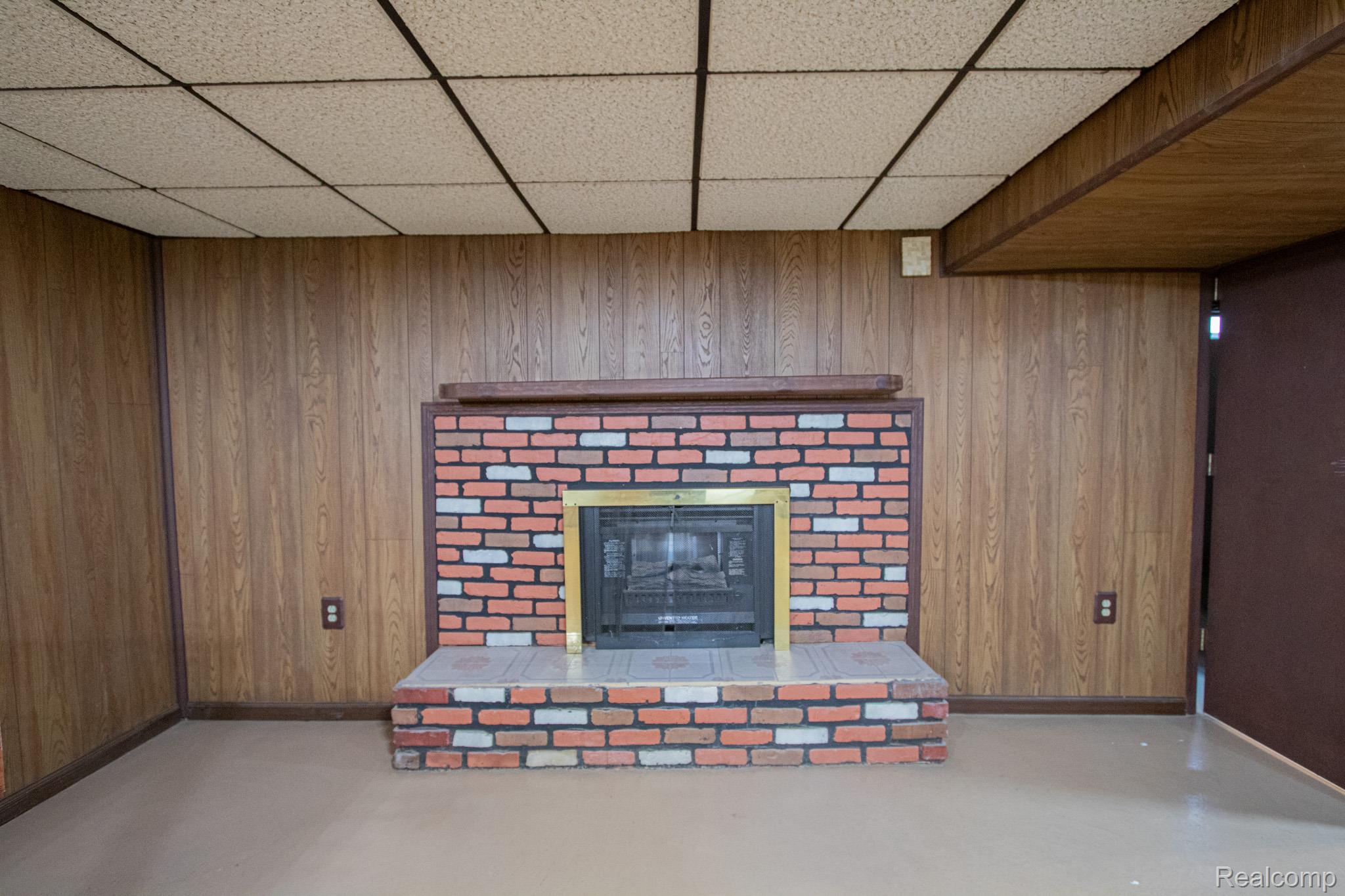31000 Fall Fraser, MI 48026 - Photo 24 of 28 Detailed view of a paneled ceiling, wood walls, a brick fireplace, and finished concrete flooring