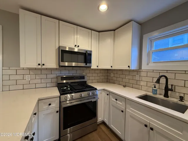 a kitchen with white cabinets stainless steel appliances and sink