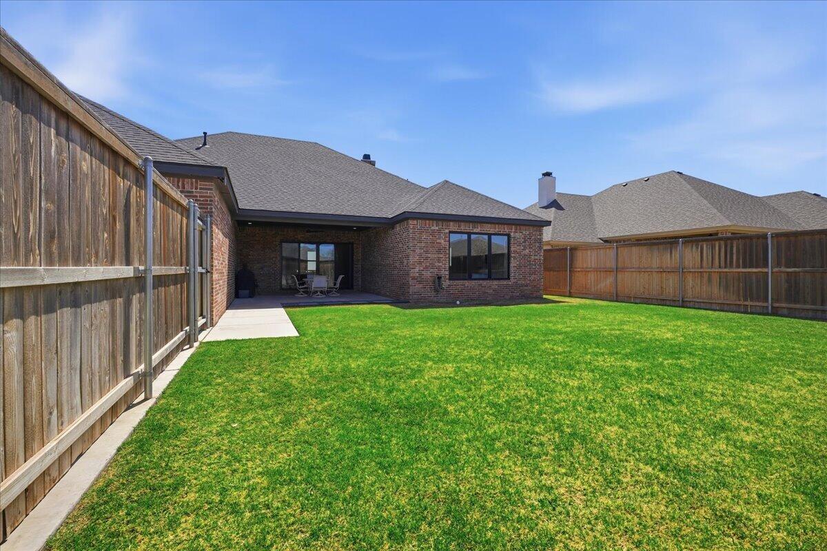 4506 140th Street Lubbock, TX 79424 - Photo 7 of 62 a view of a house with brick walls and a yard with a large tree