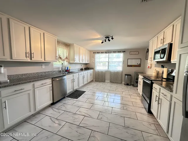 a kitchen with stainless steel appliances granite countertop a stove top oven a sink a counter space and cabinets